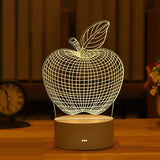 Acrylic night light with etched apple design glowing warm on a wooden base