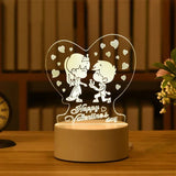Acrylic night light etched with a kissing couple design on a lit wooden base
