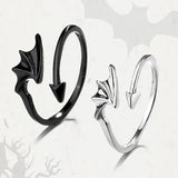 Black silhouette angel wing ring paired with silver ring on white background