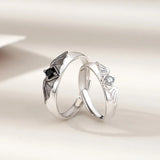 Close-up of silver angel and demon couple rings with black and clear stone accents