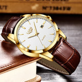 Gold case watch with brown leather strap resting on a leather bound book