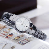 Silver steel couple watches with black dial displayed on an open magazine