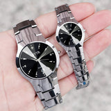 Silver steel couple watches with black dial held together in a hand