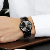 Close-up of silver steel watch with black dial worn on wrist
