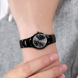 Silver steel watch with black dial worn on wrist with a brown sleeve