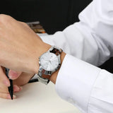 Silver steel watch with black dial worn on wrist with white dress sleeve