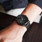 Black watch with half hollow dial and black strap worn on a wrist