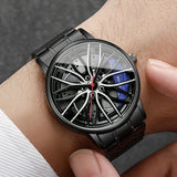 Black car wheel style watch with blue caliper accent worn on wrist with white sleeve