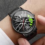 Black car wheel style watch with green caliper accent worn on wrist with white sleeve