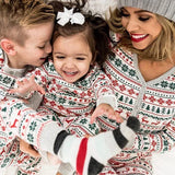 Mother and two children in matching grey Fair Isle Christmas pyjamas with a toy dog