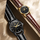 Gold black dial couple watches with brown leather straps resting on wooden surface