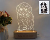 Acrylic night light etched with a dog portrait on a wooden base beside flowers