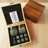 Dark wood whiskey stones box open beside its lid showing glasses and granite cubes