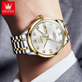 Two-tone silver and gold watch with white dial worn on wrist with a light gray sleeve