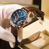 Gloved hand holding blue dial skeleton automatic watch with brown crocodile pattern strap
