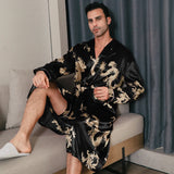 Man wearing a black silk robe with gold dragon embroidery seated at a side angle