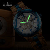 Wooden watch showing glowing green luminous hands and markers in the dark