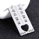 Silver stainless steel bar keychain engraved with a date and heart cutout on dark fabric