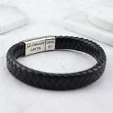 Close-up of black braided leather bracelet with engraved silver plate on marble background