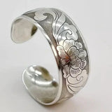 Open silver cuff bracelet with floral engraving and polished centre detail