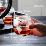 Hand holding etched world map whiskey glass with dimensions shown beside globe decanter
