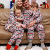 Two young children wearing matching Fair Isle Christmas pyjama sets on a sofa