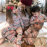 Family in matching Fair Isle Christmas pyjamas beside a decorated tree