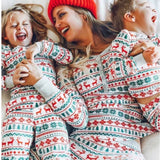 Parent and child in matching Fair Isle Christmas pyjamas with red knit hats
