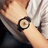Black geometric dial watch with steel bracelet worn on a wrist