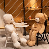 Cream and tan giant teddy bears with satin bow ties on a cafe floor