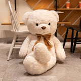 Cream giant teddy bear with satin bow tie seated beside cafe chairs