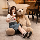 Woman sitting beside a giant tan teddy bear showing its full height