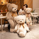 Three giant teddy bears in cream, tan and beige with satin bows beside a seated woman