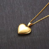 Polished gold heart photo locket on a chain against a dark textured background
