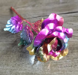 Rainbow multicolor gold plated rose resting on a rustic wooden surface