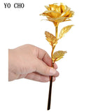 Hand holding a yellow gold plated rose with gold stem and leaves