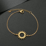 Gold chain bracelet with sunburst sun charm and extender chain on a dark background