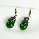 Silver vintage style earrings with green teardrop stones and ornate scrollwork