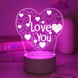 Heart shaped acrylic LED night light etched with I Love You glowing pink on a round base