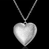 Plain polished silver heart photo locket on a fine chain against a black background