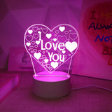 Heart shaped LED lamp lit pink on a bedside surface in a softly lit bedroom