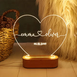Etched heart outline night light with two names, glowing warm white on a wooden base