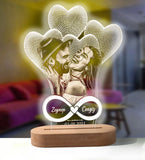 Heart shaped etched acrylic lamp glowing purple on a wooden base in a living room