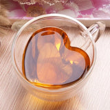 Heart shaped double wall glass cup filled with dark coffee on floral background