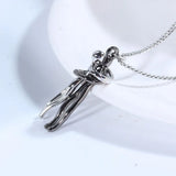 Black and silver hugging couple pendant necklaces draped over a white vase