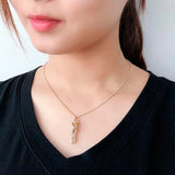 Woman wearing a gold hugging couple pendant necklace with a black top