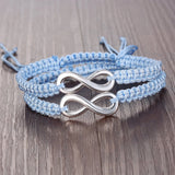 Pair of light blue braided rope infinity bracelets on a wooden surface