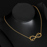 Gold infinity name necklace draped over a black display stand