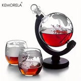 Etched globe whiskey decanter filled with spirit on wood stand beside two matching map glasses
