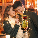 Couple holding a lit glass dome rose with fairy lights glowing in the dark